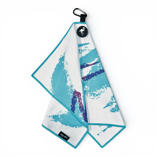 The 90s Party Cup Golf Towel, a 24x16 in premium double-sided microfiber towel with teal trim and an abstract teal and purple design, hangs from a black carabiner and features a magnetic round tag with a flamingo logo.
