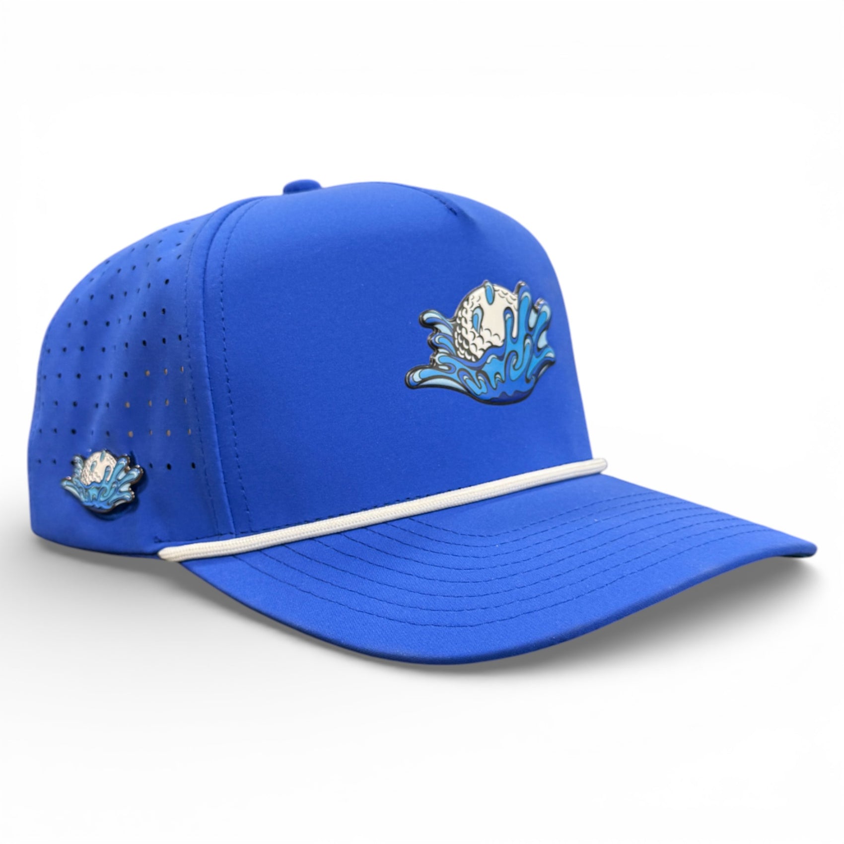The Water Ball Golf Hat is a blue snapback cap with white and blue embroidered wave and golf ball designs, ventilation holes, a white rope accent above the brim, and a built-in magnetic ball marker holder with marker included. Adjustable fit.