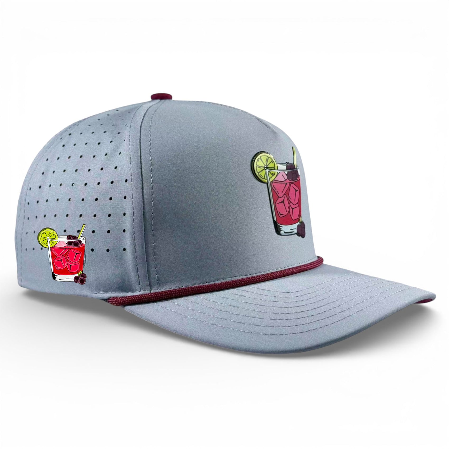 The Transfusion Golf Hat is a light gray adjustable snapback cap with maroon trim, perforated side panels, two embroidered cocktail images, and a built-in magnetic ball marker holder with marker—ideal for stylish golf performance.