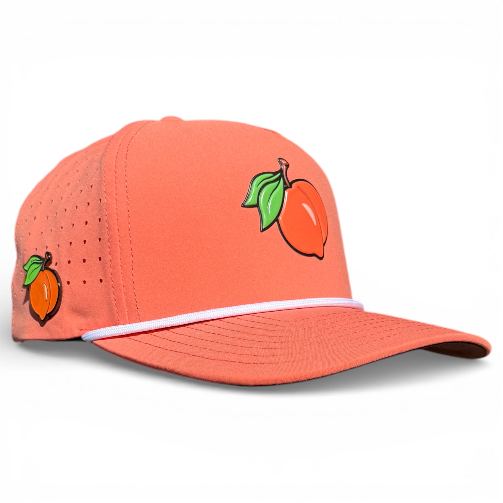 The Just Peachy Golf Hat is a peach snapback cap featuring small peach fruit illustrations, a white accent stripe, perforated side panel for ventilation, an adjustable fit, plus a built-in magnetic ball marker holder with marker included.