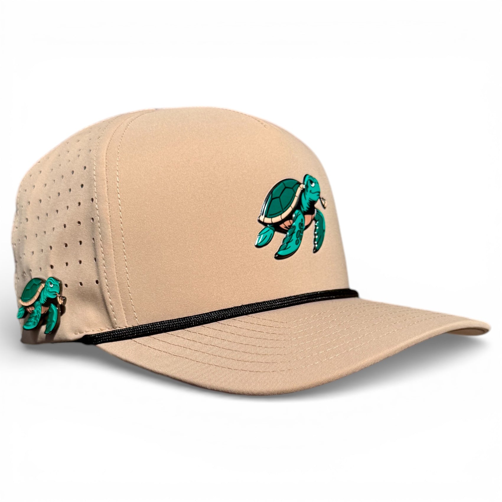 The Salty Turtle Golf Hat is a beige snapback cap featuring a green sea turtle embroidery, matching turtle charm, black trim, ventilation holes, and an adjustable fit. It includes a built-in magnetic ball marker holder with marker. One size fits most.