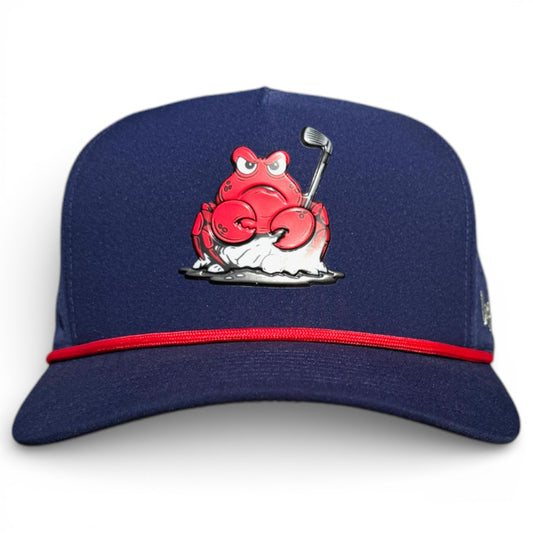 The Crab Trap Golf Hat is a navy adjustable snapback cap with a cartoon red crab golfing on sand, a white background, red band above the brim, and built-in magnetic ball marker holder plus included marker. One size fits all.