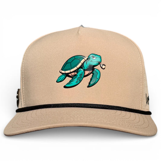 The Salty Turtle Golf Hat is a beige snapback cap with a cartoon sea turtle smoking a pipe on the front, black rope detail, built-in magnetic ball marker holder, and included marker. Adjustable and one size fits all.