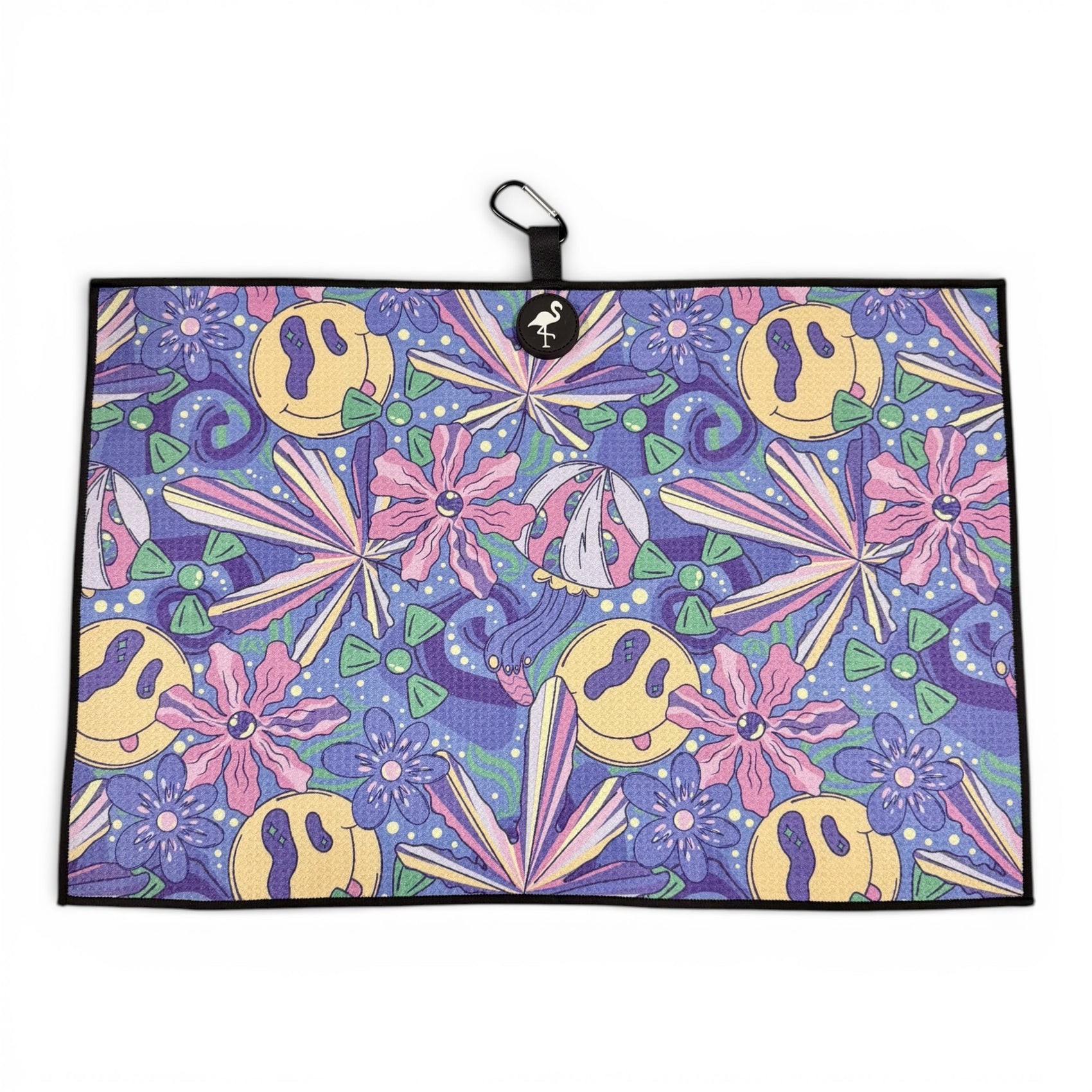 The Purple Haze Golf Towel is a 24x16 in double-sided microfiber towel with a psychedelic blue pattern, yellow smiley faces, pink and lavender flowers, green triangles, and purple leaves. Includes a black loop with white logo plus carabiner clip.