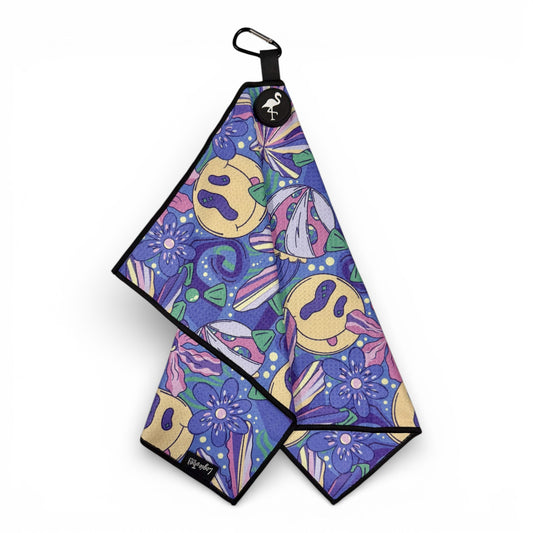 The Purple Haze Golf Towel is a 24x16 in premium double-sided microfiber towel, featuring a 90s-inspired print with yellow smiley faces, purple flowers, abstract shapes, and comes with a heavy-duty magnetic carabiner clip.
