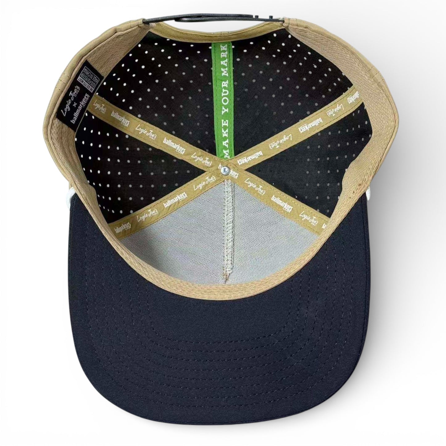 Inside view of the Hunting Birdies Golf Hat: features tan seams, polka dot black lining, a green band with "MAKE YOUR MARK," gold logo tape, navy blue underside. Snapback cap with built-in magnetic ball marker holder and adjustable fit.