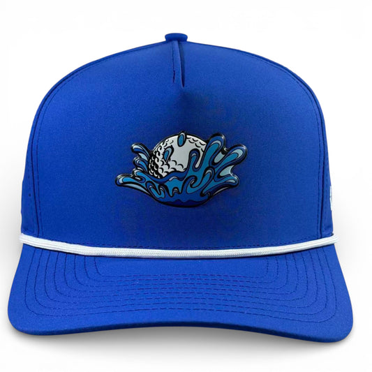 The Water Ball Golf Hat is a royal blue snapback cap with a white cord, featuring an embroidered golf ball splashing into blue water. Adjustable for comfort, it includes a built-in magnetic ball marker holder and marker.