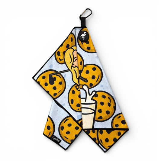 The Milk & Cookies Golf Towel | Cart Girl features a cartoon woman with cookies on a light blue background. Made from premium double-sided microfiber, it measures 24x16 in and includes a heavy-duty magnetic carabiner clip for easy hanging.